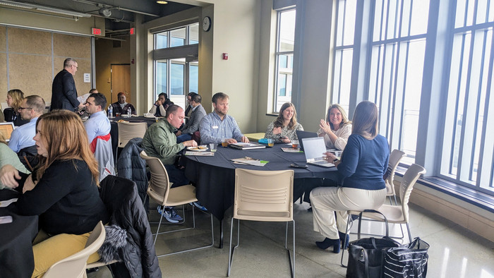 Participants sitting at round tables talking and smiling